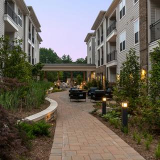 A modern apartment complex with a well-lit pathway and lush landscaping.
