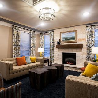 A modern living room featuring comfortable sofas, a stylish fireplace, and vibrant decorative cushions.