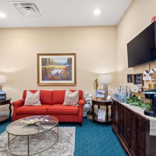 A cozy living room with a red sofa, coffee table, wall-mounted TV, and decorative elements.