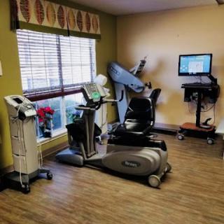 A well-equipped fitness and rehabilitation room featuring various exercise machines and a workstation.