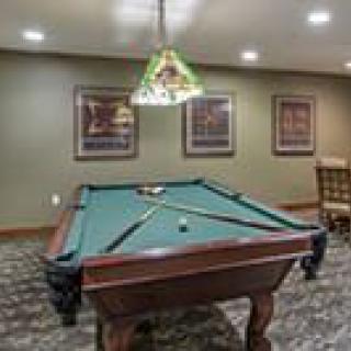 A cozy game room featuring a billiards table under decorative lighting.