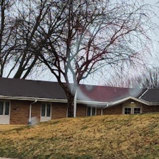 A serene view of a brick building beside a bare tree on a cloudy day.