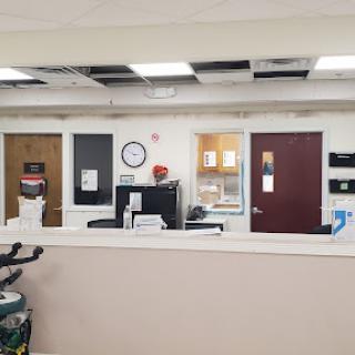 A view of the reception area in a medical office, featuring multiple doors and a clock on the wall.