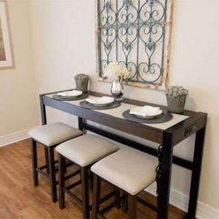 A stylish dining setup featuring a high table with bar stools and elegant wall decor.