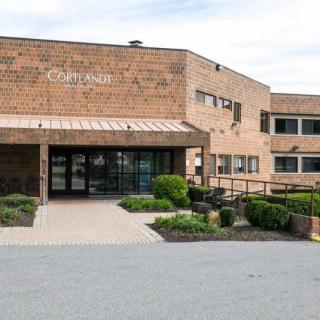 The entrance to a brick healthcare facility with surrounding greenery.