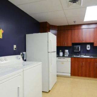 A combined laundry and kitchen area with appliances including a washing machine, dryer, refrigerator, and dishwasher.