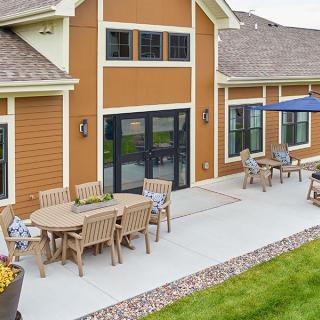A spacious outdoor patio with tables, chairs, and an umbrella, adjacent to a building.