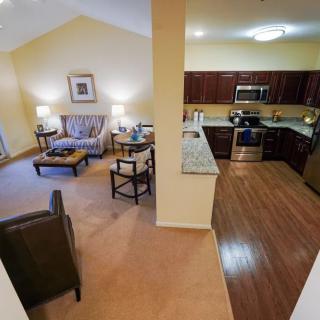 An open floor plan combining a cozy living room and a modern kitchen with wood flooring and carpet.