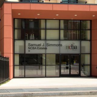 The entrance to a modern building with large glass windows and signage.