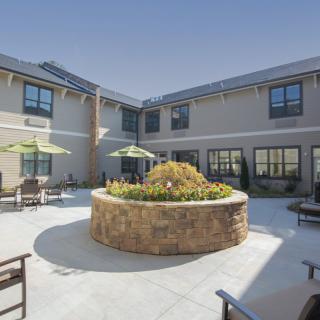 A sunny courtyard with outdoor seating and landscaping in a modern building.