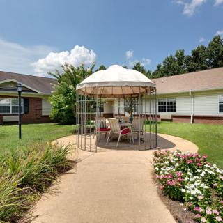 A well-maintained garden with a gazebo and outdoor seating area on a sunny day.