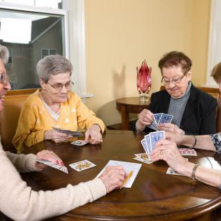 A group of elderly women enjoying a game of cards around a table.