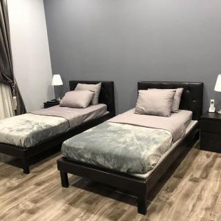 A modern bedroom with two twin beds, side tables, and lamps on a hardwood floor.