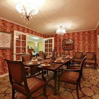 A classic dining room with ornate wallpaper and a formal table setting.