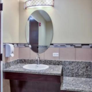 A modern bathroom with a granite countertop and an oval mirror.
