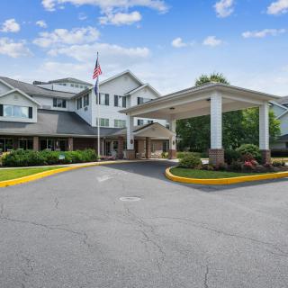 A well-maintained entrance of a residential building with landscaping and an American flag.