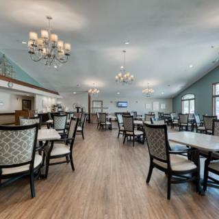 A spacious and elegant dining area with chandeliers, featuring modern furniture and wooden flooring.