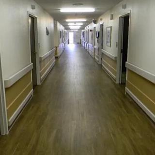 An empty, well-lit hallway in a healthcare facility.