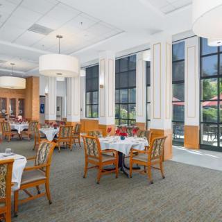A spacious and elegantly designed restaurant dining area with large windows and neatly arranged tables and chairs.