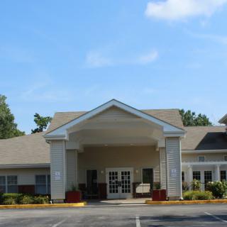 A view of a residential building entrance with a gabled roof and landscaped surroundings.