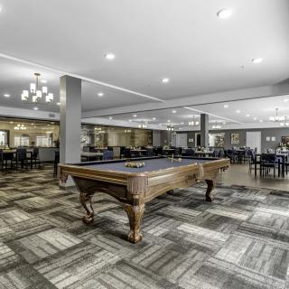 A spacious recreation room with a billiards table and modern seating arrangements.