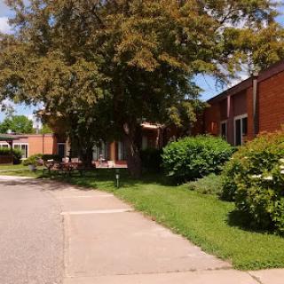 A serene view of a brick building surrounded by lush greenery and pathways.