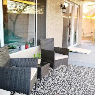 A cozy outdoor patio space featuring stylish wicker furniture and an intricate patterned rug.