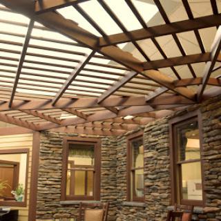 An elegant interior featuring a wooden pergola with stone walls, allowing natural light to filter through.