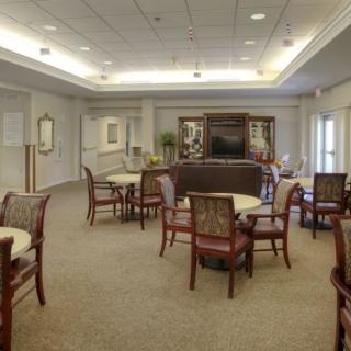 A spacious and well-lit seating area with tables and chairs, suitable for gatherings or meetings.