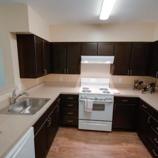 A modern kitchen with dark cabinets and a white stove.