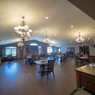 A spacious dining hall with elegant chandeliers and arranged seating.