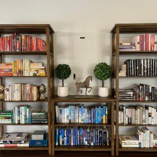 A cozy and organized bookshelf displaying a variety of colorful books and decorative plants.