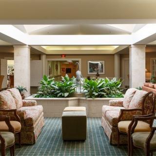 Cozy lobby with comfortable seating and indoor plants under a skylight.