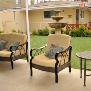 A patio with comfortable seating overlooking a backyard with a fountain.