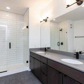A modern bathroom featuring a spacious shower, double sink vanity, and sleek black fixtures.
