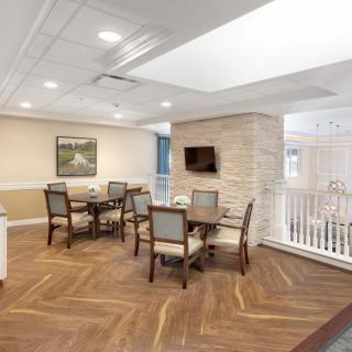 A modern dining area with tables, chairs, and a mounted television on a wooden floor.