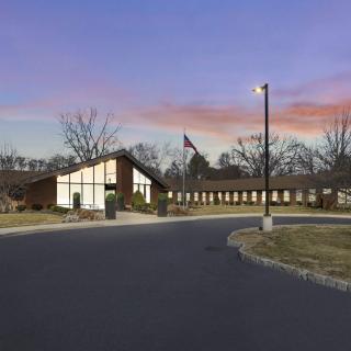 A building complex at sunset with a flagpole and surrounding trees.