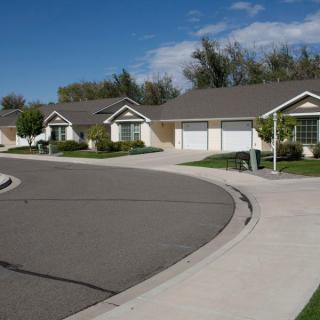 A quiet suburban neighborhood with a row of houses along a curved street under a clear blue sky.