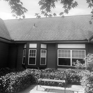 A view of a charming house with a well-kept garden in black and white.