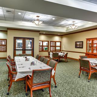 A well-lit dining room with neatly arranged tables and chairs, featuring elegant interior design.