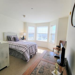 A bright bedroom with natural light, featuring a neatly made bed and cozy decor.