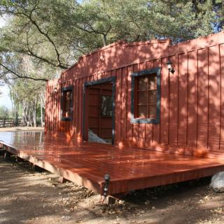 A rustic wooden cabin surrounded by trees, with a spacious porch.