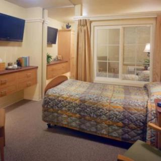A cozy bedroom with a single bed, television, and ample furniture.