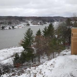 A serene winter landscape overlooking a lake surrounded by snow-covered trees.
