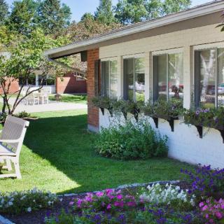 A beautifully landscaped garden with vibrant flowers and a comfortable chair beside a house.