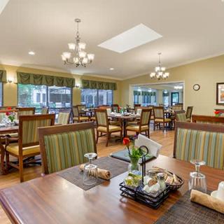 A spacious and elegant dining area with neatly arranged tables and chairs, featuring ambient lighting from chandeliers.