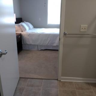 A view from the doorway into a cozy bedroom with a large bed and natural light.