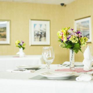 An elegantly set dining table with floral centerpieces and white dinnerware.