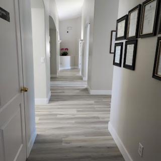 A well-lit hallway featuring framed photographs and a modern wooden floor design.