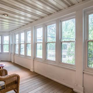 A bright sunroom with large windows and wicker furniture.